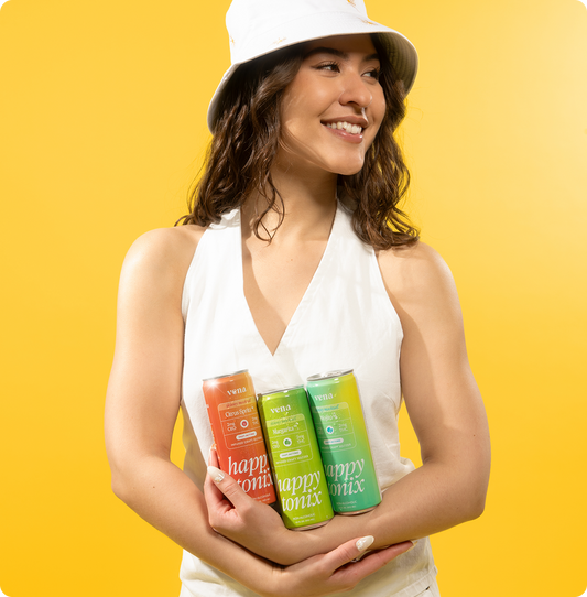 Smiling woman holding three Happy Tonix THC seltzer cans with vena logo against yellow background