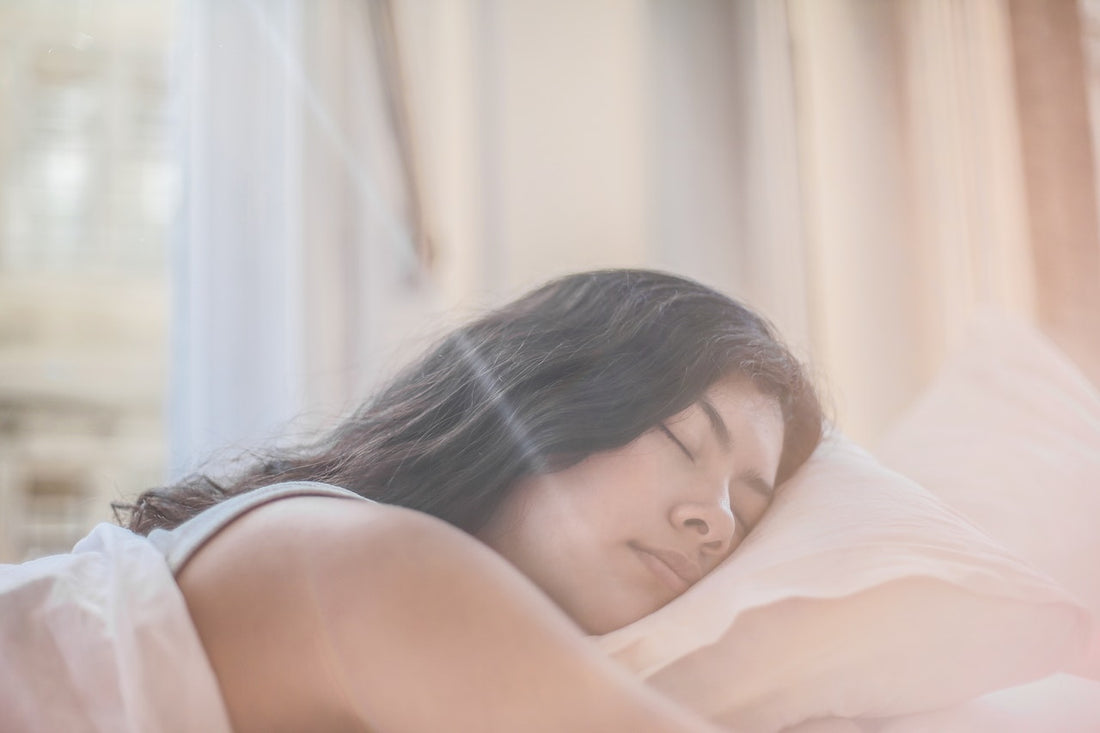 Young woman sleeping on her side on a pillow in a sunlit bedroom, conveying restorative sleep.