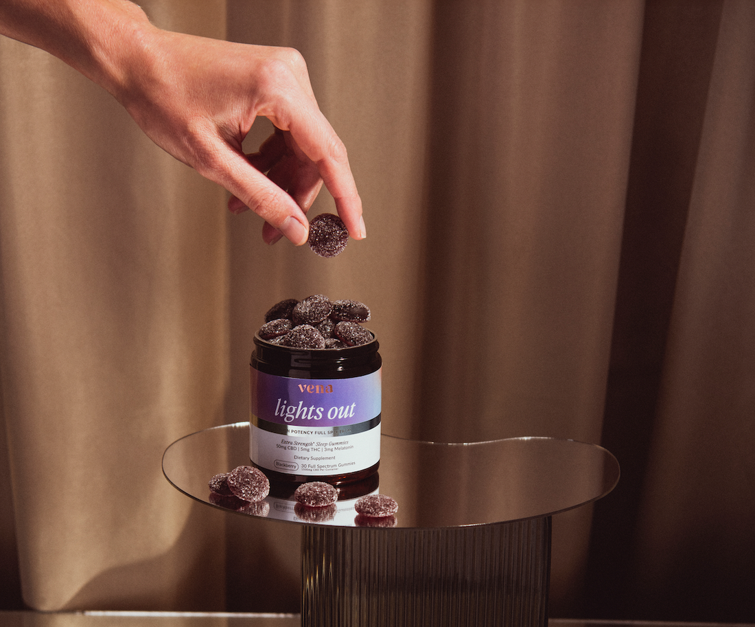 Jar labeled 'vena lights out' filled with sugar-coated Blackberry gummies, hand picking one.